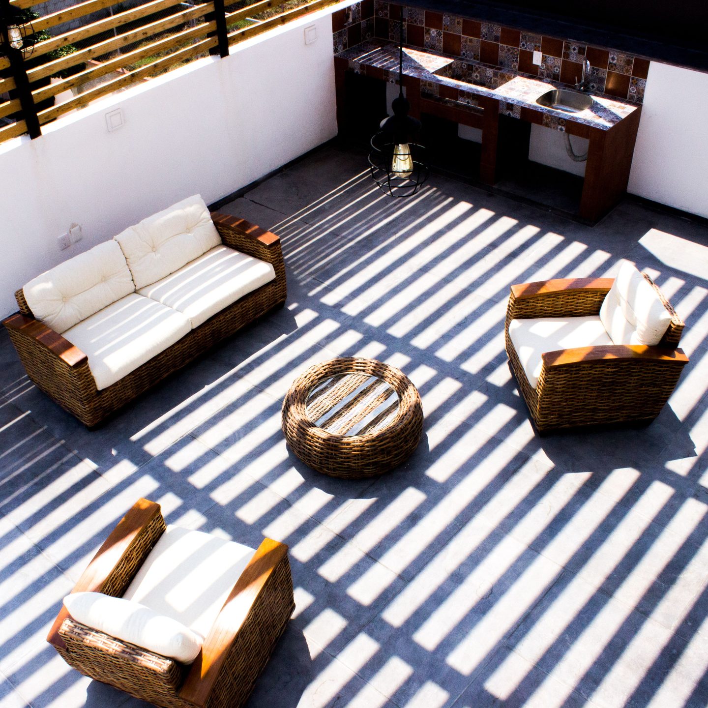 Terraza vista desde arriba con sofás de ratán y sombra de listones