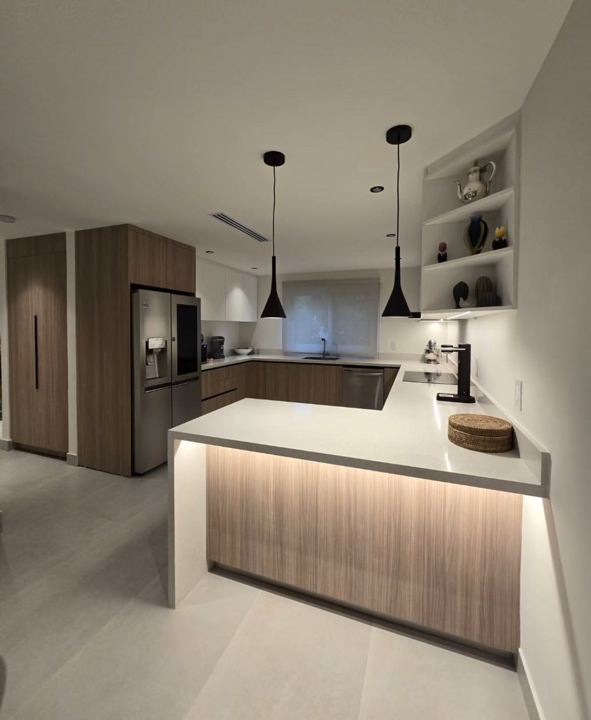 Cocina en L con barra iluminada y lámparas colgantes